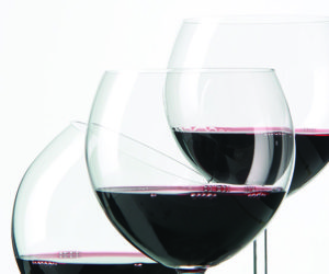 three red wine glasses, two upright and one at an angle
