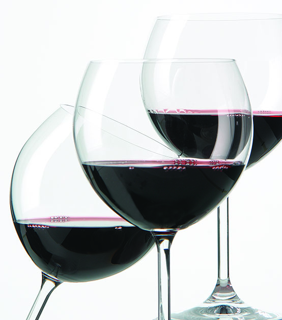 three red wine glasses, two upright and one at an angle