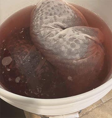 Bagged blueberries floating in a bucket of juice.