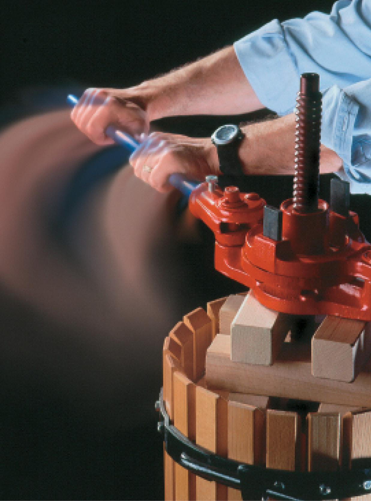 Arms pulling on a wine press handle.