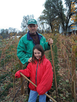 Man and a girl wearing parkas and holding gardening tools.
