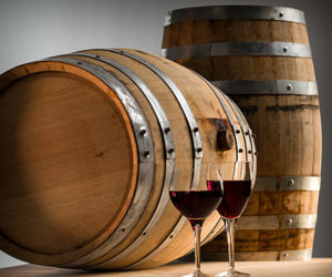 two glasses red wine and two wine barrels