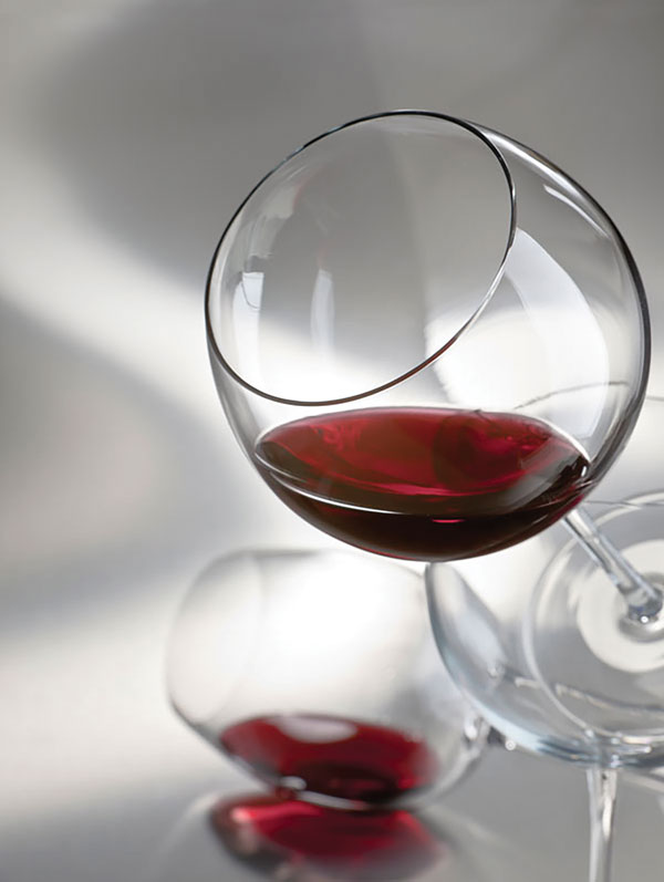 tilted red wine glass with a glass mirror background