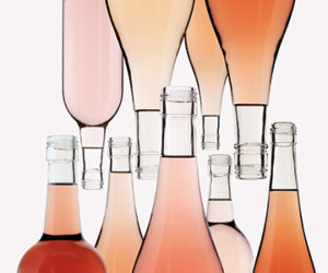 bottle of rosé wine uncorked, many upright while others appear upside down.
