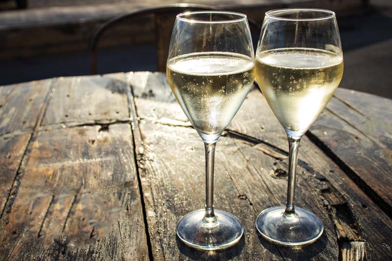 two glasses of sparkling wine sitting on an aged wooden table top