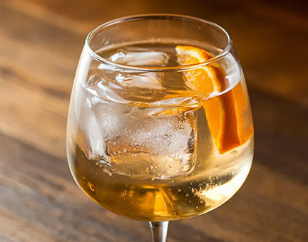 White wine spritzer with a slice of orange and ice.